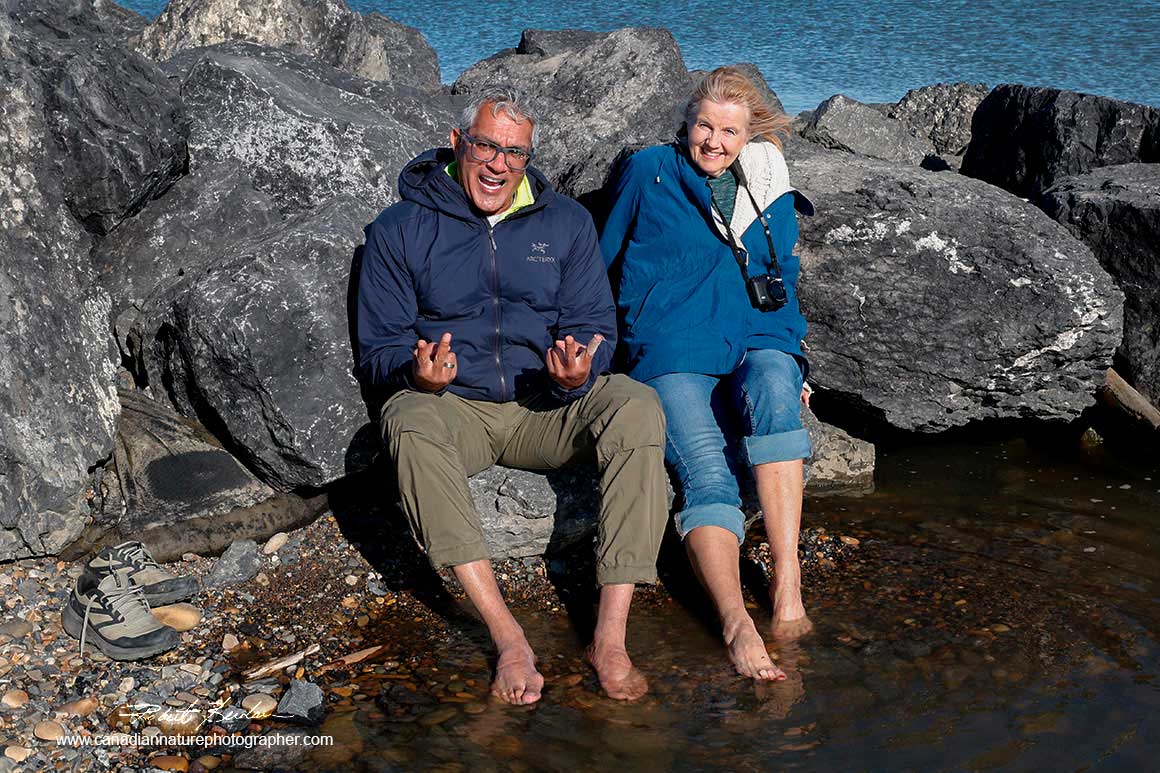 Kamal and Donna tipping their feet into the Arctic ocean in Tuktoyaktuk